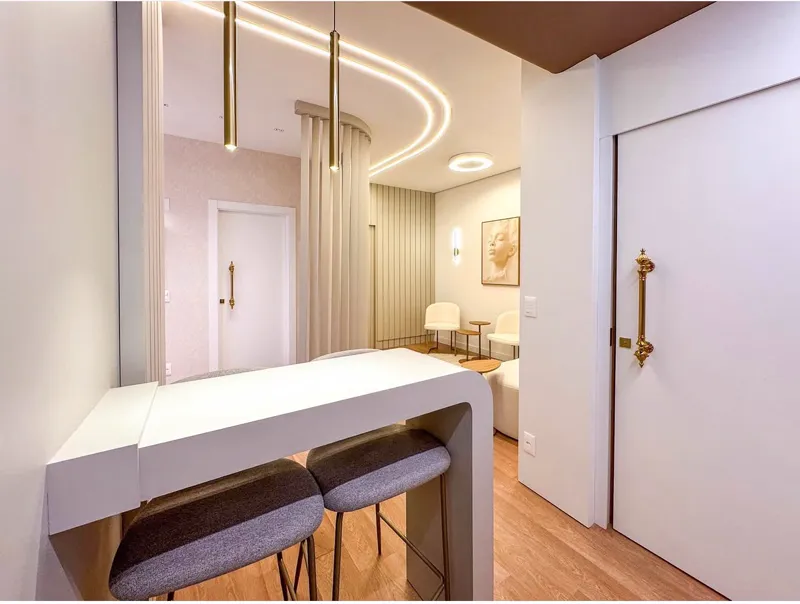 Recepção boutique com a sinalização em bronze da Bravô Clinic, iluminada em tom champagne, na Praia Brava, Itajaí