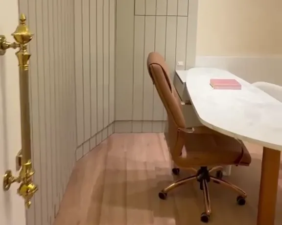 Consultório boutique com ripado em madeira clara, cadeira em couro caramelo e mesa de mármore em formato orgânico